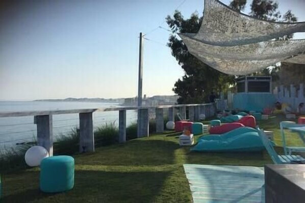 A seaside patio with outdoor seating and a view of the ocean.