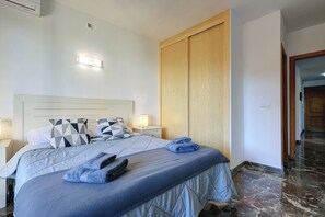 A bedroom with a bed, nightstands, a wooden wardrobe, and a marble floor. - Spacious 2 bedroom apartment with sea view! (Municipality of Fuengirola)