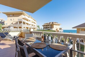 A balcony with a table set for dining, overlooking a coastal area with buildings and the sea. - Spacious 2 bedroom apartment with sea view! (Municipality of Fuengirola)