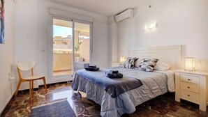 A hotel room with a bed, a nightstand, a chair, and a sliding glass door to the outside. - Spacious 2 bedroom apartment with sea view! (Municipality of Fuengirola)