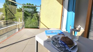 A balcony with a table holding a book titled 'Klimatyczny Kotobrzeg', a plate with a pastry, and a glass of water. - Apartament Pawie Oczko - 365PAM (Kolobrzeg)