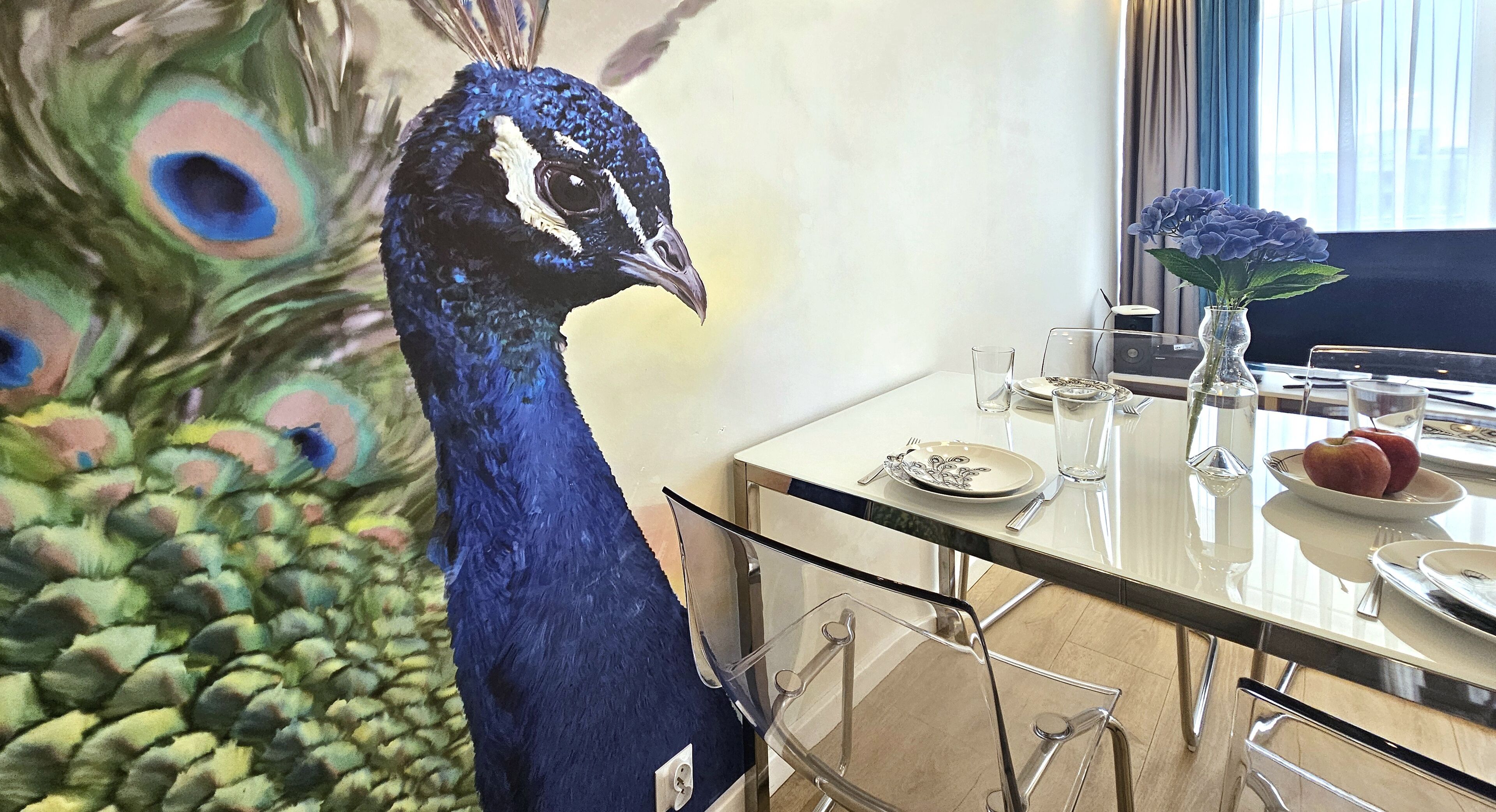 Comedor con mesa de vidrio, sillas y una estatua de un pavo real.