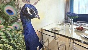 A dining area with a glass table, chairs, and a peacock statue. - Apartament Pawie Oczko - 365PAM (Kolobrzeg)