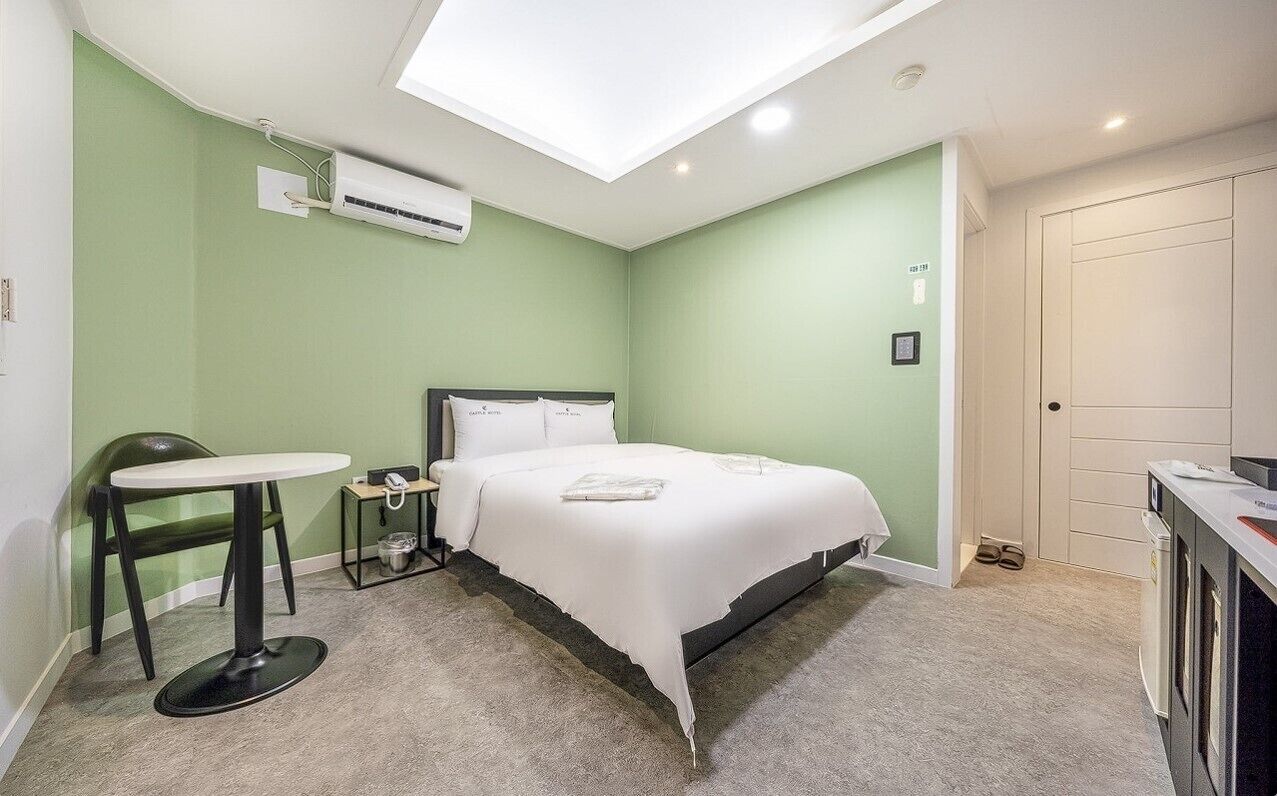 Un dormitorio con una cama, una mesita, una silla, una mesita de noche y un armario.