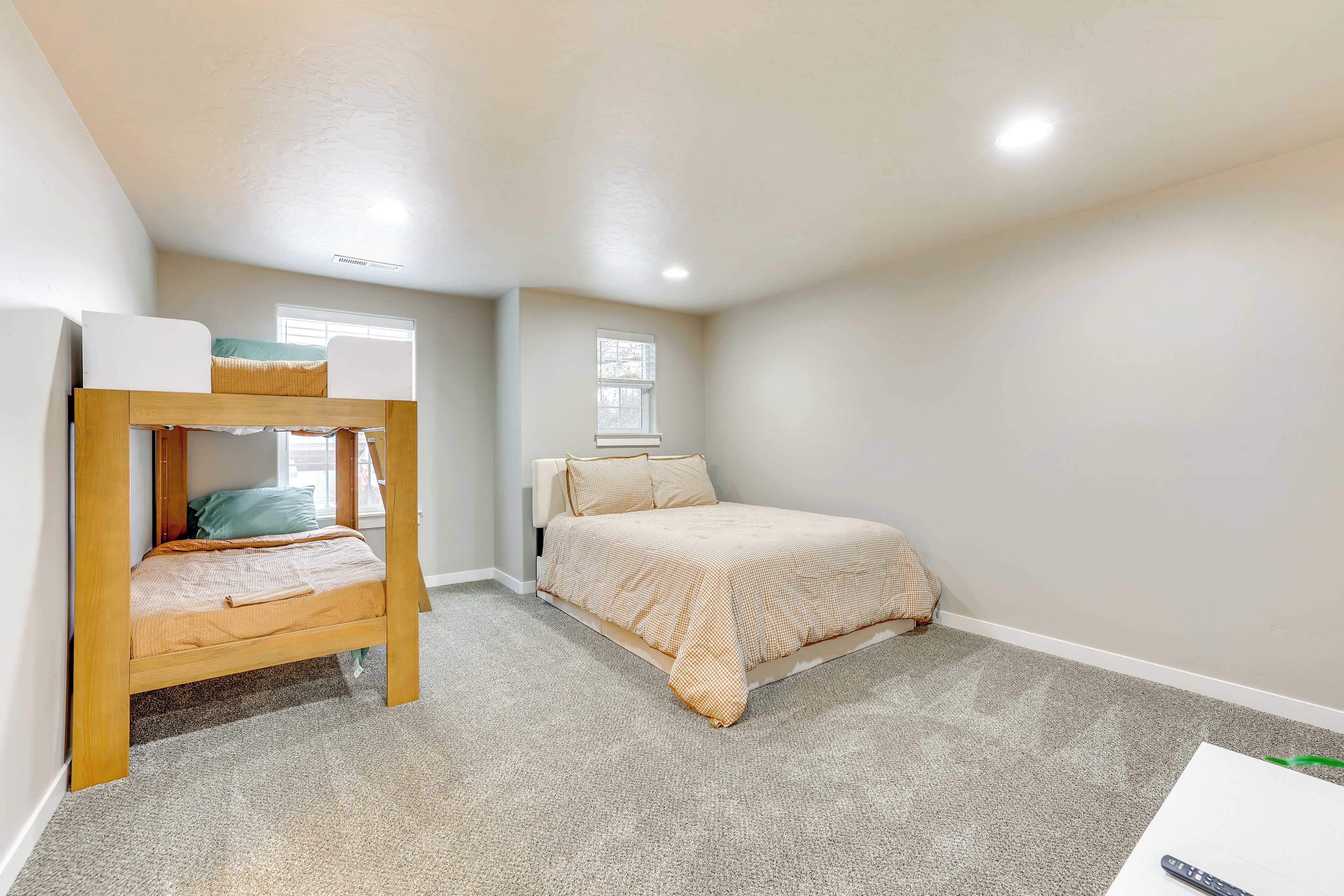 A bedroom with a bunk bed, a single bed, and a carpeted floor.