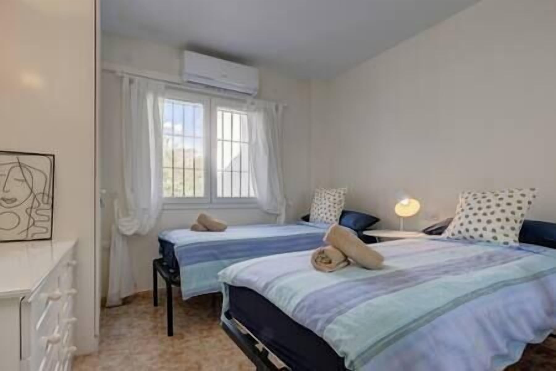 Un dormitorio con dos camas, un escritorio y una ventana con cortinas.