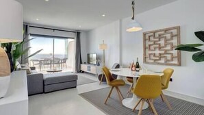 A modern hotel room with a dining area, a sofa, and a view of the outdoors. - New 2 Bed Penthouse @ Estepona Hills With Sea View (Estepona)