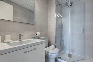 Bathroom features a glass-enclosed shower area, a sink with a countertop, and a toilet.