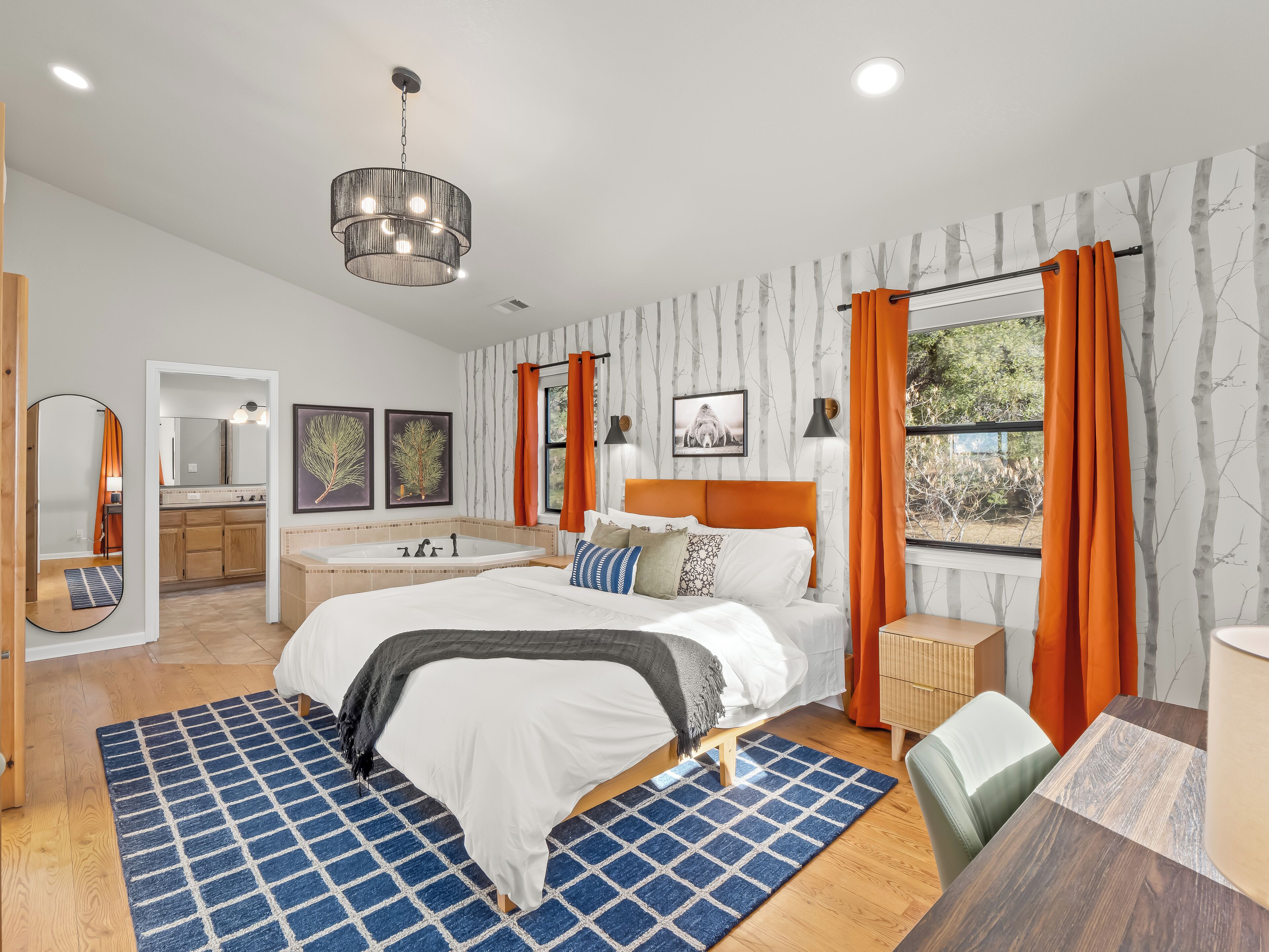 A modern bedroom with a large bed, a bathroom with a bathtub, and a dining area.