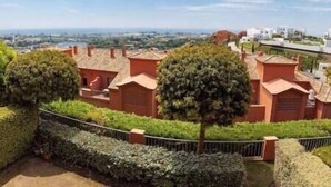 Un quartier résidentiel composé de maisons en terrasses, d’un chemin pavé et offrant une vue lointaine sur la mer.