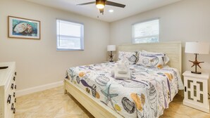 A bedroom with a bed, ceiling fan, two windows, and a nightstand with a lamp. - Walk to Fort Myers Beach: Family-friendly Getaway! (Fort Myers Beach)