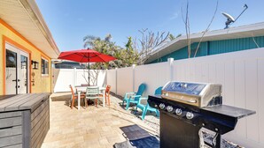 A backyard with a barbecue grill, outdoor furniture, and a red umbrella. - Walk to Fort Myers Beach: Family-friendly Getaway! (Fort Myers Beach)