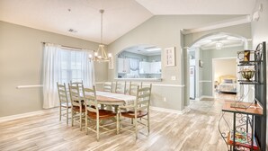 A dining area with a wooden table and chairs, a chandelier, and a view into the kitchen. - 535 Arbor Trace - Barefoot Resort Rentals (North Myrtle Beach)