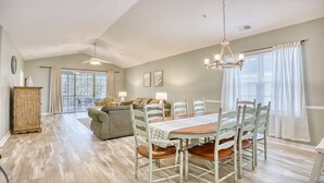 A spacious living area with a dining table, chairs, a sofa, and a ceiling fan. - 535 Arbor Trace - Barefoot Resort Rentals (North Myrtle Beach)