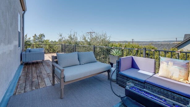 A balcony with a wooden deck, a sofa, and a chair.