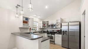 A modern kitchen with white cabinetry, stainless steel appliances, and a central island. - Oceanside Village - Beautiful 3BR 2BA - Golf Cart Included! (Surfside Beach)