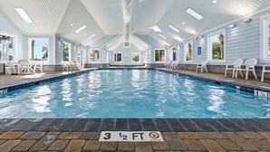 An indoor swimming pool with a 3 1/2 ft depth, surrounded by white chairs and a covered roof with skylights. - Oceanside Village - Beautiful 3BR 2BA - Golf Cart Included! (Surfside Beach)