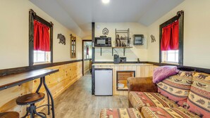 A cozy cabin-style room with a wooden interior, a kitchenette, a sofa, and a small table.
