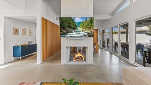 Ein modernes Interieur mit Kamin, einem blauen Schrank und einem großen Fenster.