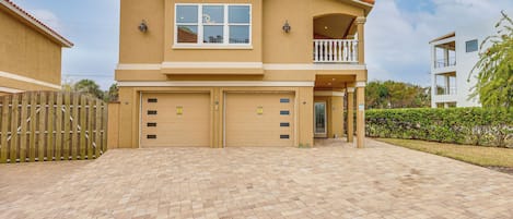 Een tweelaags huis met een balkon, een garage en een verharde oprit.
