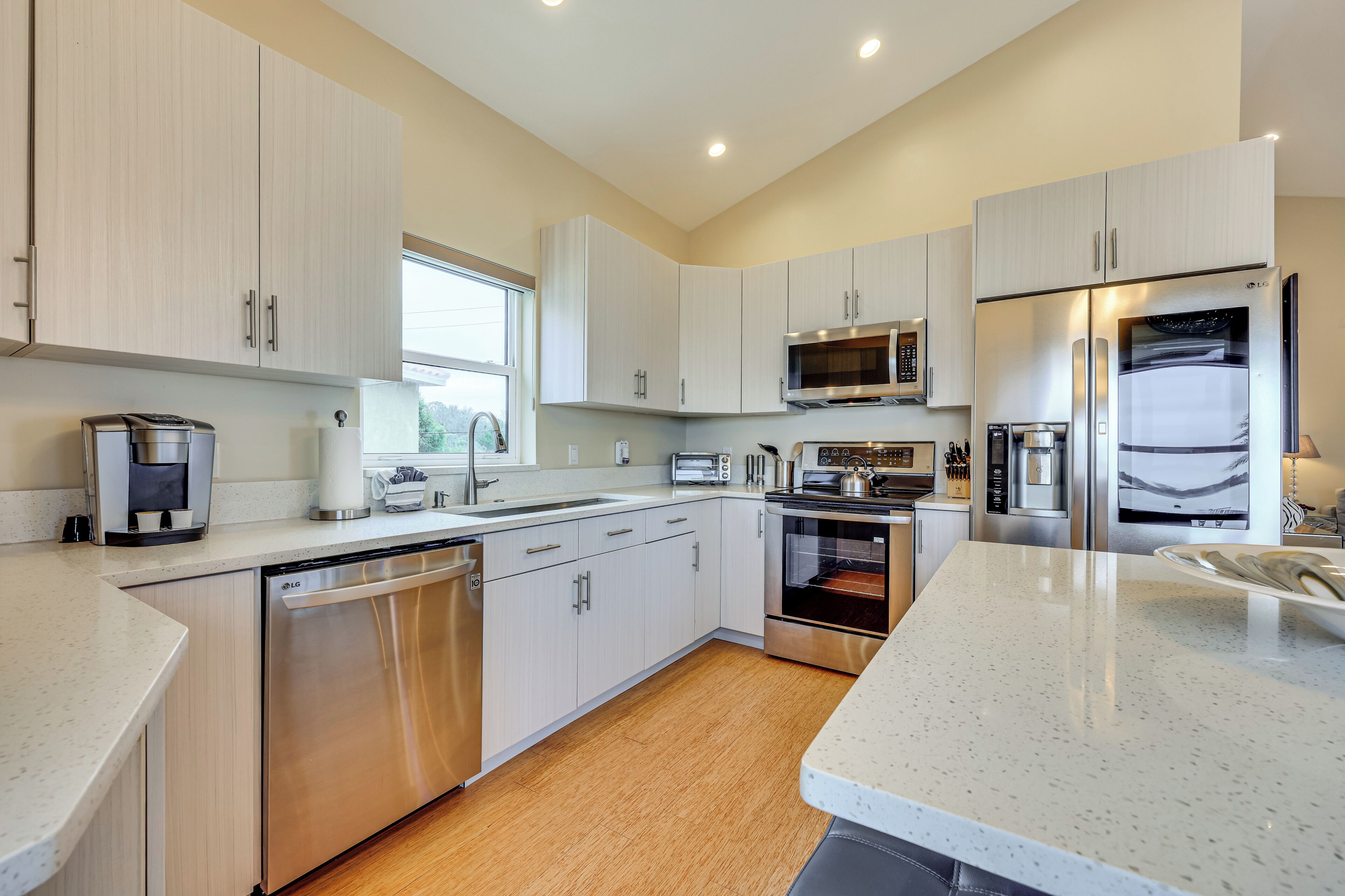 A modern kitchen with white cabinetry, stainless steel appliances, and a large island.