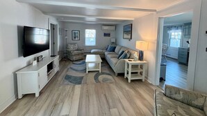 A spacious living room with a flat-screen TV, a sofa, a coffee table, and a lamp. - The perfect cozy Chatham getaway awaits you! (Chatham)