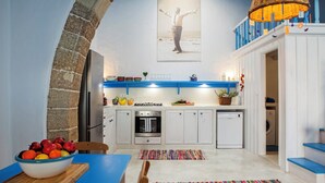 Une cuisine avec des meubles blancs, un plan de travail bleu et un panier suspendu.