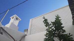 Un bâtiment blanc avec une cheminée et une clôture en treillis.