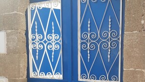Une porte bleue ornée de motifs en métal et un heurtoir de porte blanc.