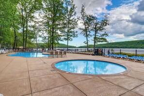 A pool area with lounge chairs and a view of a hilly landscape.