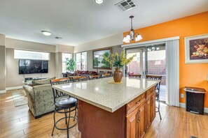 A spacious kitchen with a large island, wooden cabinets, and a dining area with a sofa and chairs. - Stay & Play in Las Vegas: Spacious Home for Groups (Las Vegas)