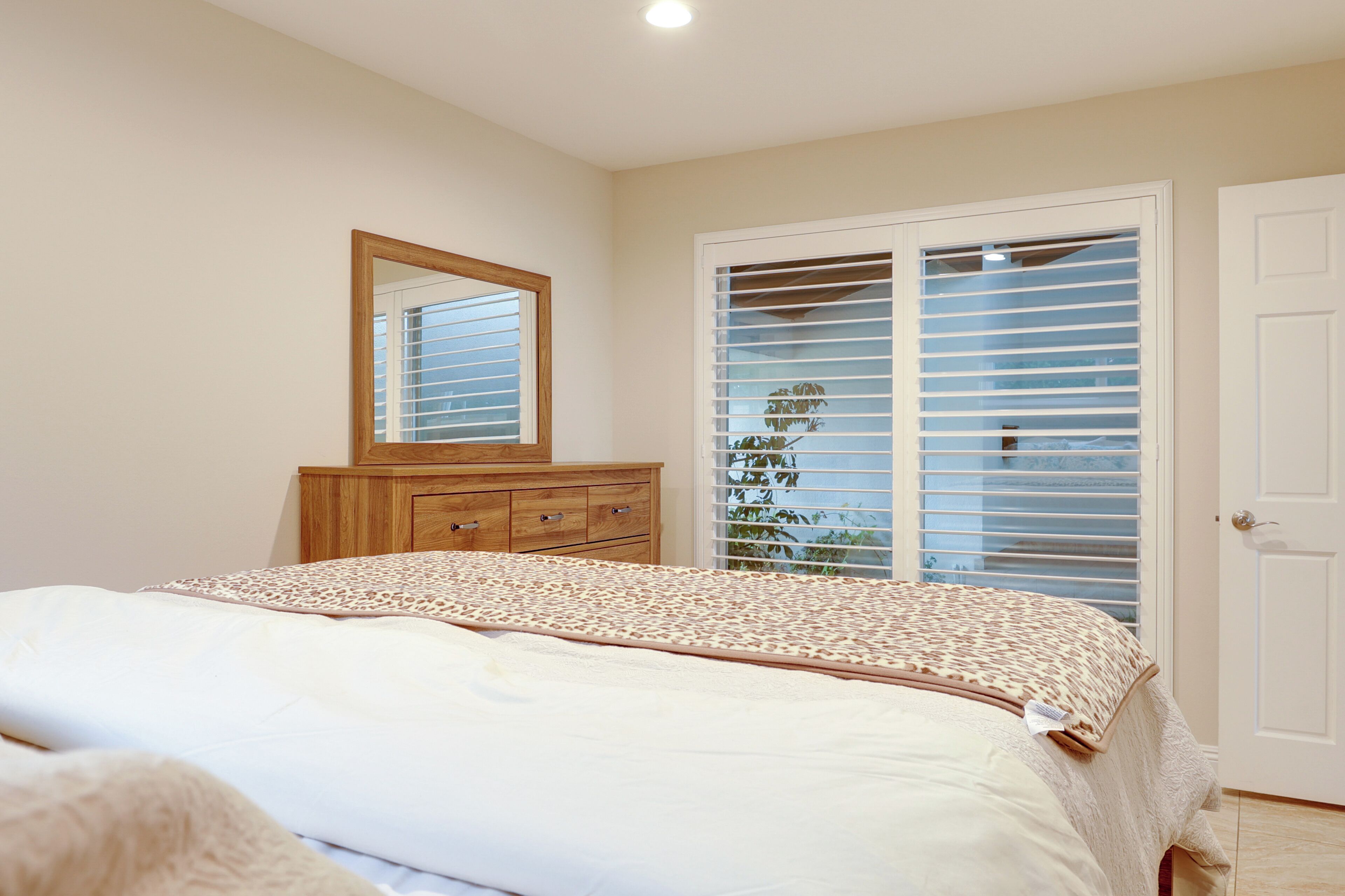 Un dormitorio con cama, cómoda, espejo y armario con puertas correderas.