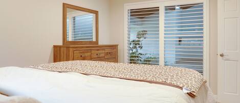 Un dormitorio con cama, cómoda, espejo y armario con puertas correderas.