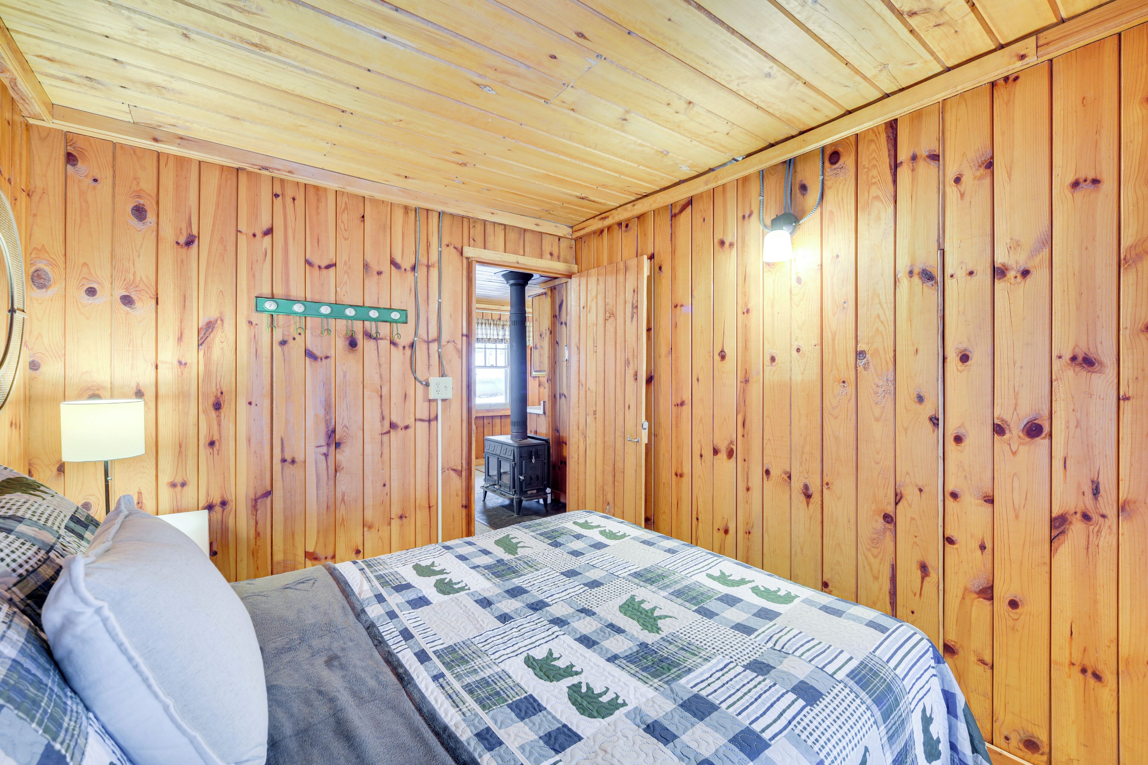 A wooden-paneled room with a bed, a lamp, and a heater.