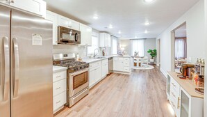 A modern kitchen with stainless steel appliances, white cabinetry, and wooden flooring.