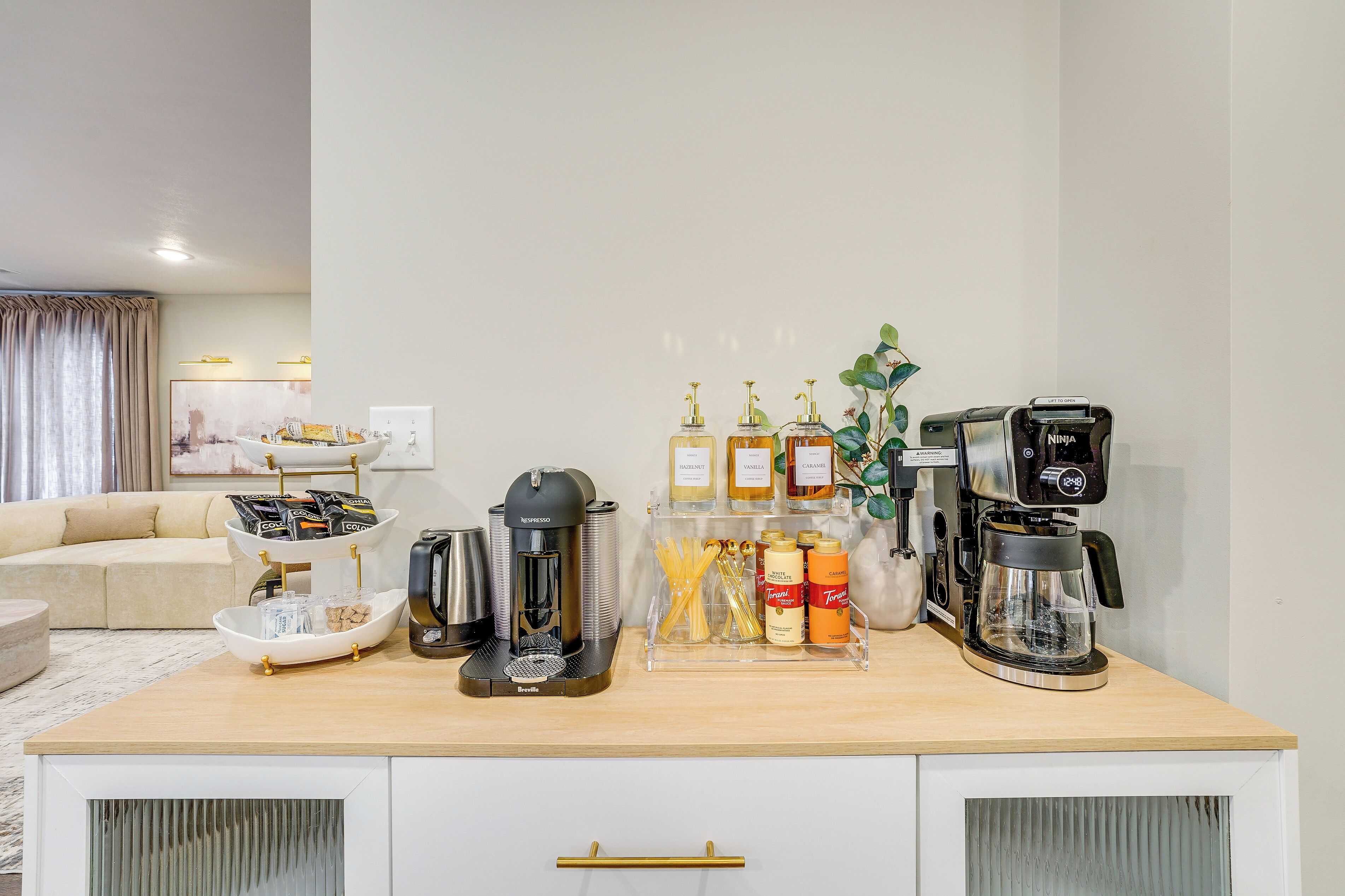 A well-organized kitchen area with a coffee machine, tea station, and various condiments.