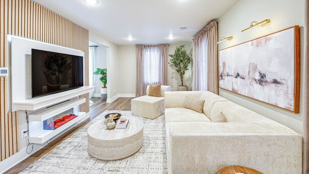 A modern living room with a flat-screen TV, a sectional sofa, a coffee table, and a large abstract painting on the wall.