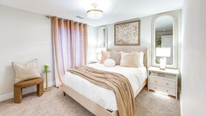 A bedroom with a large bed, bedside tables, a nightstand, a bench, and a mirror.