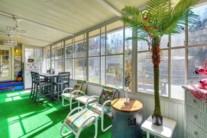 A sunroom with a green floor, white furniture, and a large window. - < 1 Mi to Boat Ramp: Canal-front Retreat in Astor! (Astor)