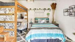 A bedroom with a bunk bed, a desk, and a chair. There is a bed with a striped bedspread, a wall-mounted shelf with plants, and a hanging light fixture. - < 1 Mi to Boat Ramp: Canal-front Retreat in Astor! (Astor)