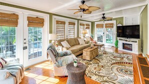 A spacious living room with a sofa, armchair, and a television. - < 1 Mi to Boat Ramp: Canal-front Retreat in Astor! (Astor)