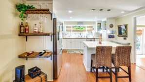 A modern kitchen with white cabinets, a built-in wine rack, and a dining area with wicker chairs. - < 1 Mi to Boat Ramp: Canal-front Retreat in Astor! (Astor)