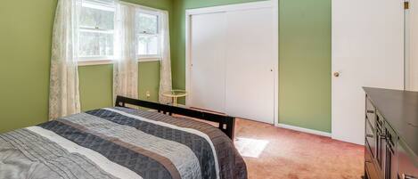 A bedroom with a bed, a dresser, a ceiling fan, and a window with curtains.