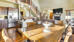 Un vaste espace dédié à la salle à manger, avec une grande table en bois, entourée de chaises en bois, et un four encastré.