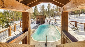 Une terrasse en bois avec une piscine, entourée de neige et d’arbres.
