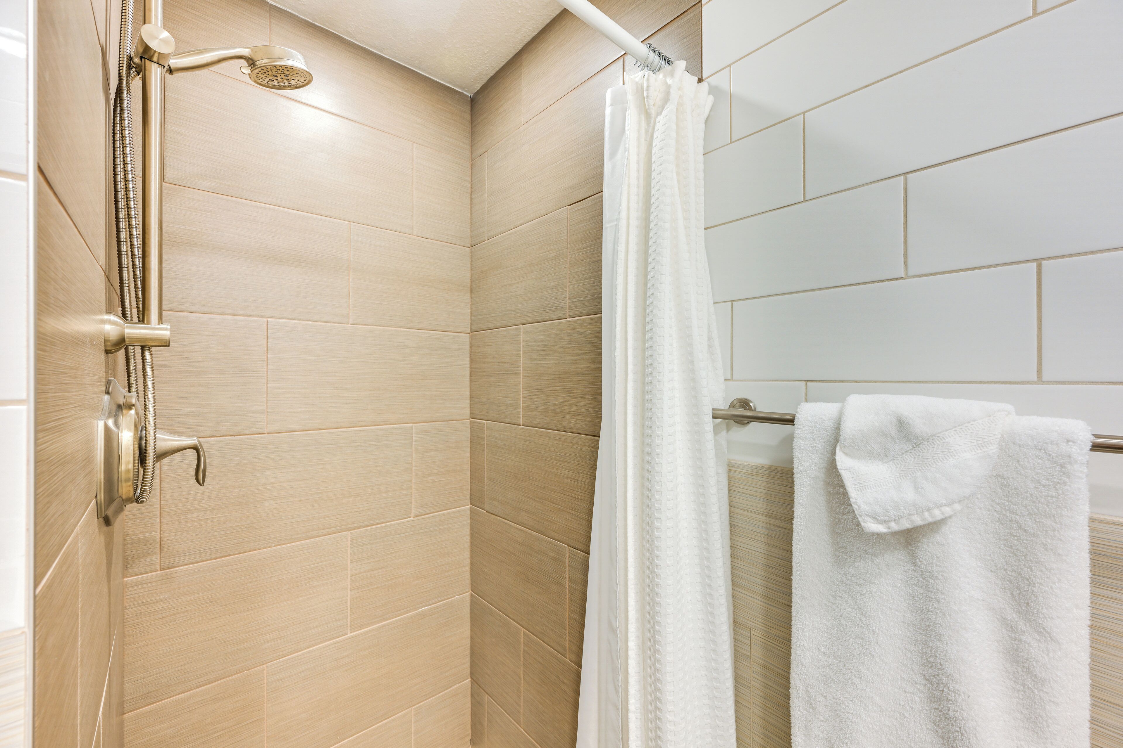 Ducha con cabezal de ducha de mano y puerta de vidrio.