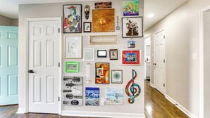 Un corridoio con una parete decorata da diverse opere d'arte incorniciate, tra cui dipinti e fotografie.