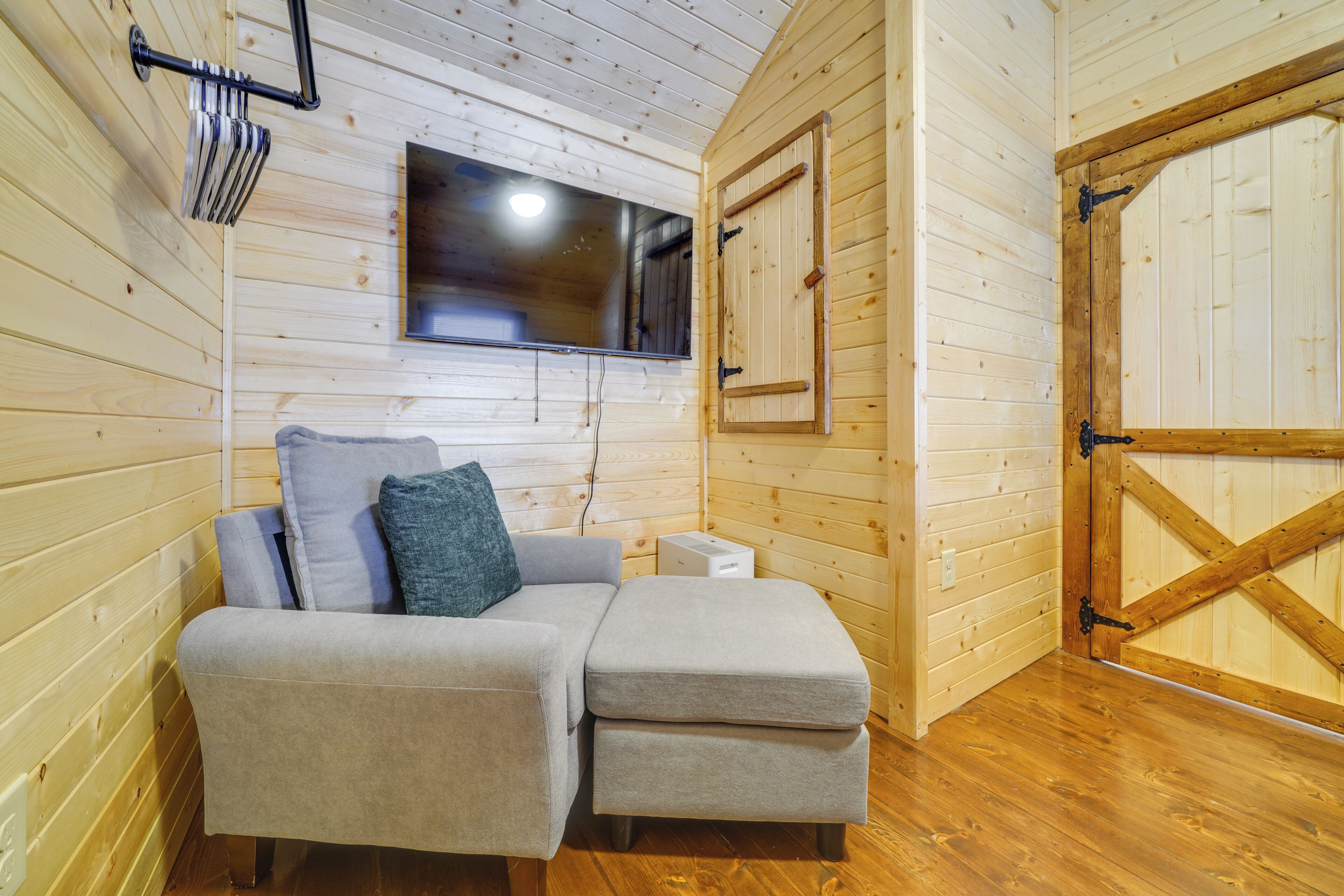 Ein gemütlicher Holzraum mit einer Couch, einem an der Wand befestigten Fernseher und einer großen Holztür.