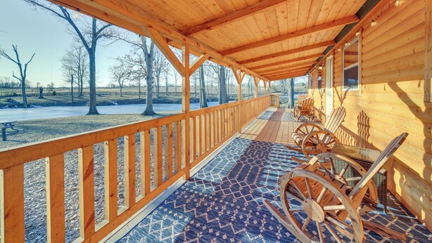Une véranda en bois, abritée, avec un sol à motifs, des chaises en bois et une vue sur un paysage enneigé.