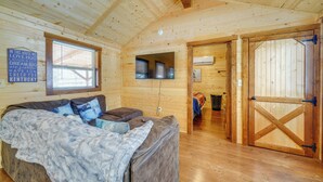 L’intérieur d’un chalet confortable, avec un grand lit, un téléviseur et une porte en bois.